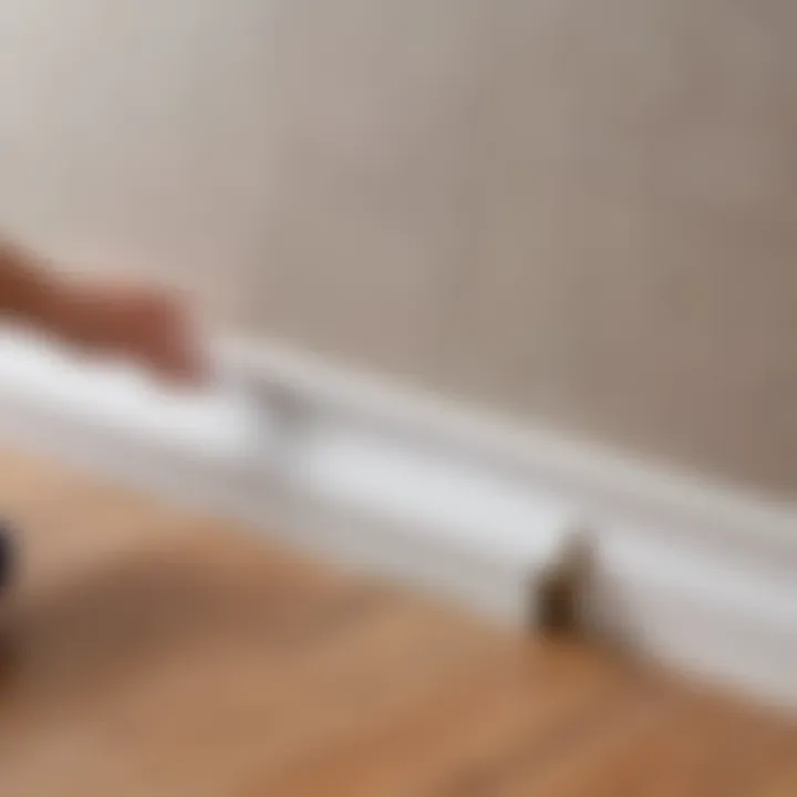 Close-up of a baseboard being attached to a wall with adhesive