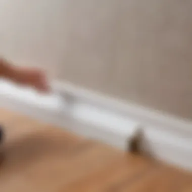 Proper Attachment Methods for Baseboards Close-up of a baseboard being attached to a wall with adhesive